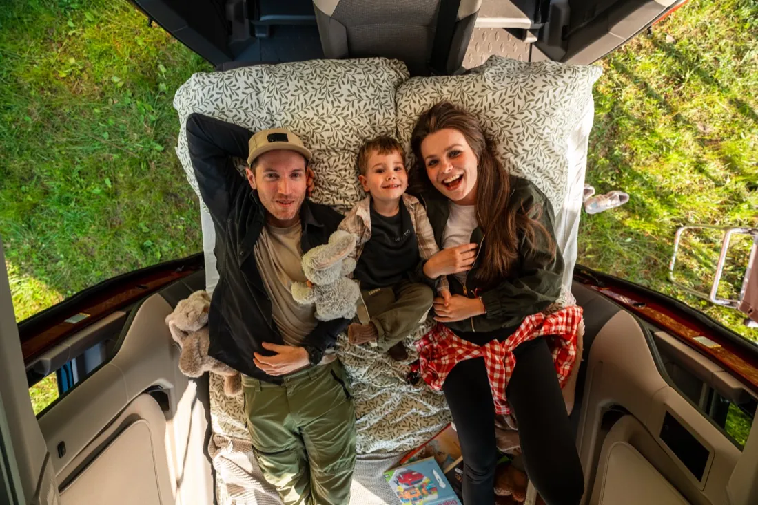 Family lying in bed in a Volkswagen California